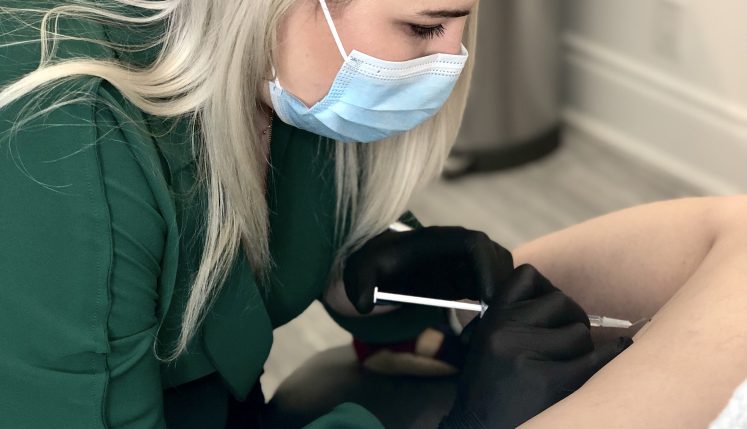 A clinician performs sclerotherapy on spider veins, using a fine injection to treat visible blood vessels on the leg during a vein treatment visit.
