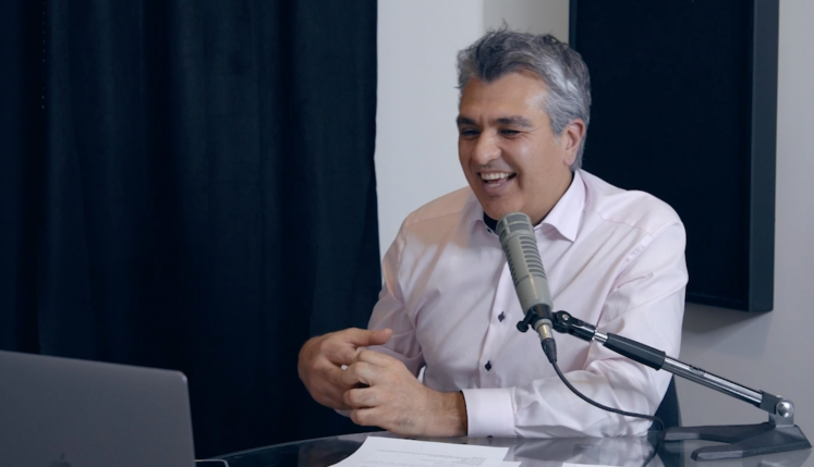 A smiling man speaks into a studio microphone during a discussion on celebrating diversity in aesthetics with Allergan Aesthetics’ Eric Tse.