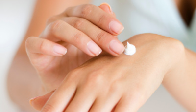 Close-up of a hand applying a small amount of cream to the wrist, showcasing skincare application.