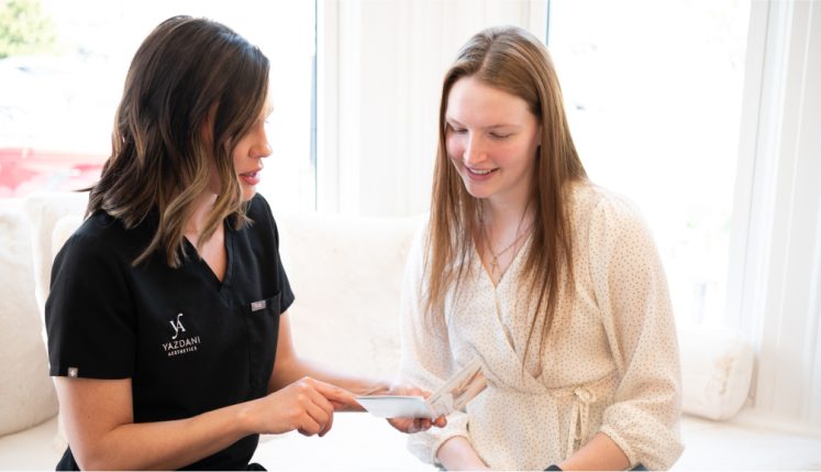 A professional discussing treatment options with a client in a consultation setting at Yazdani Aesthetics.