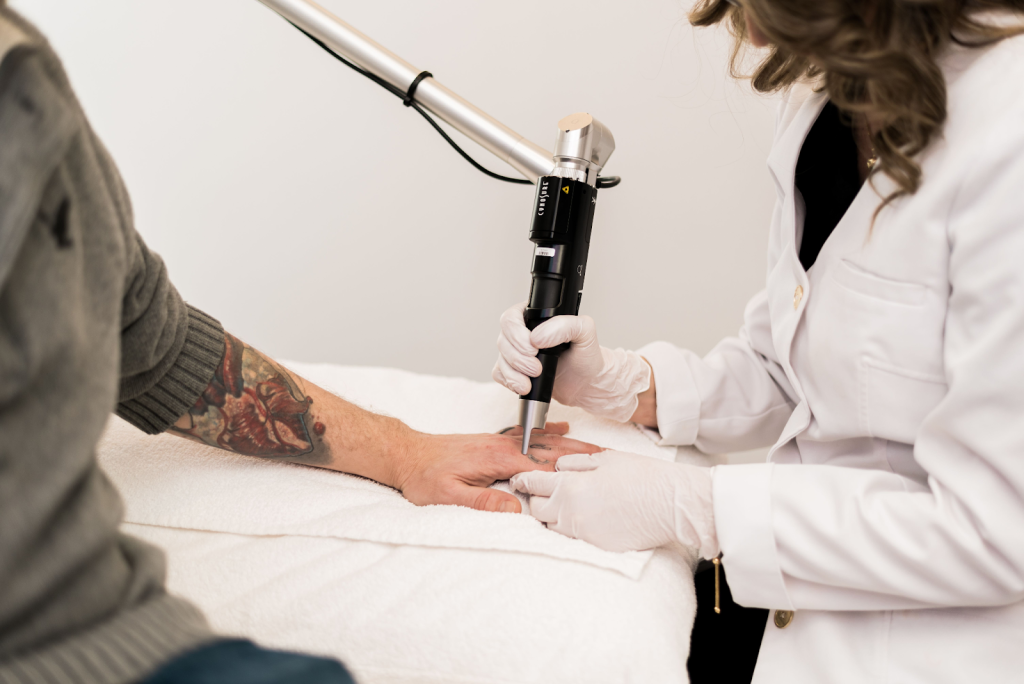 A laser technician at Yazdani Aesthetics is removing a tattoo for a man.